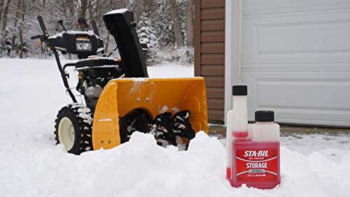 Snow blower in the snow with Stabil storage bottles nearby