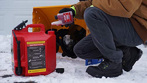 Person refueling a snowblower with a red fuel canister in a snowy setting