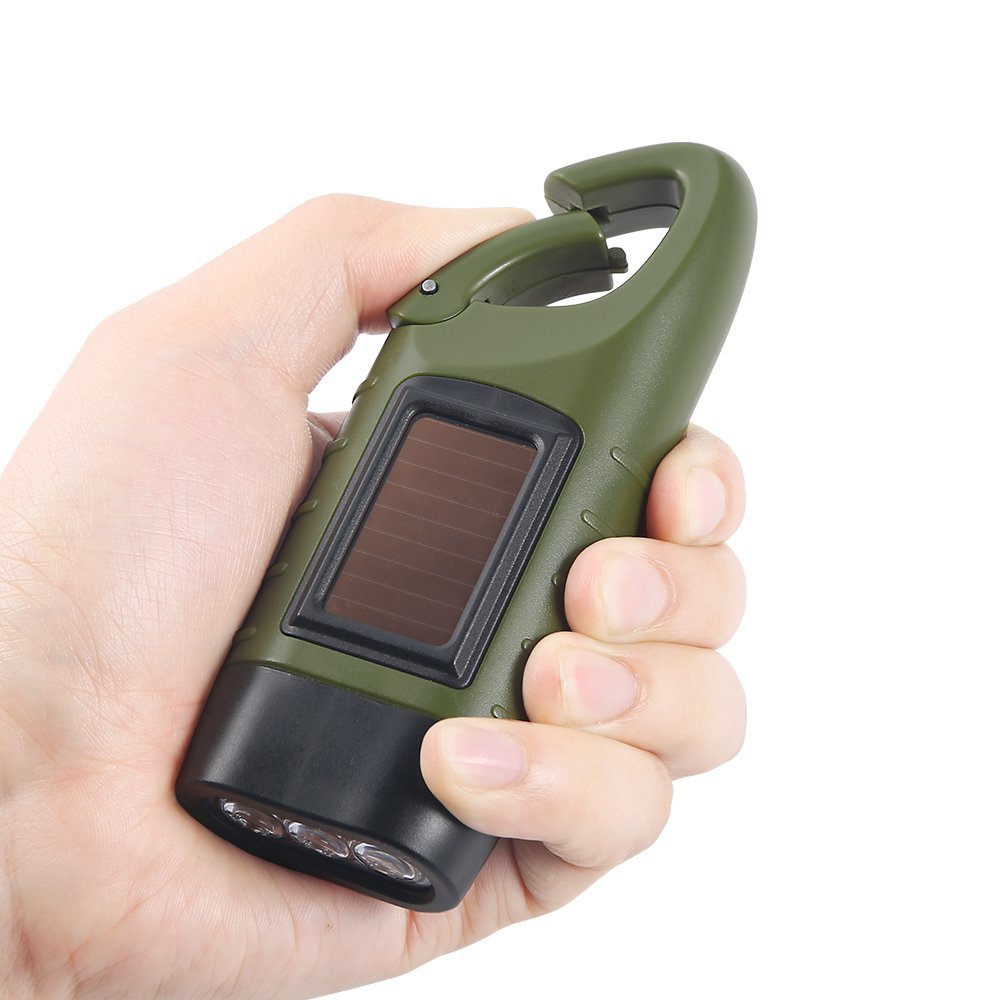 Hand holding a green and black portable device with a solar panel on a white background