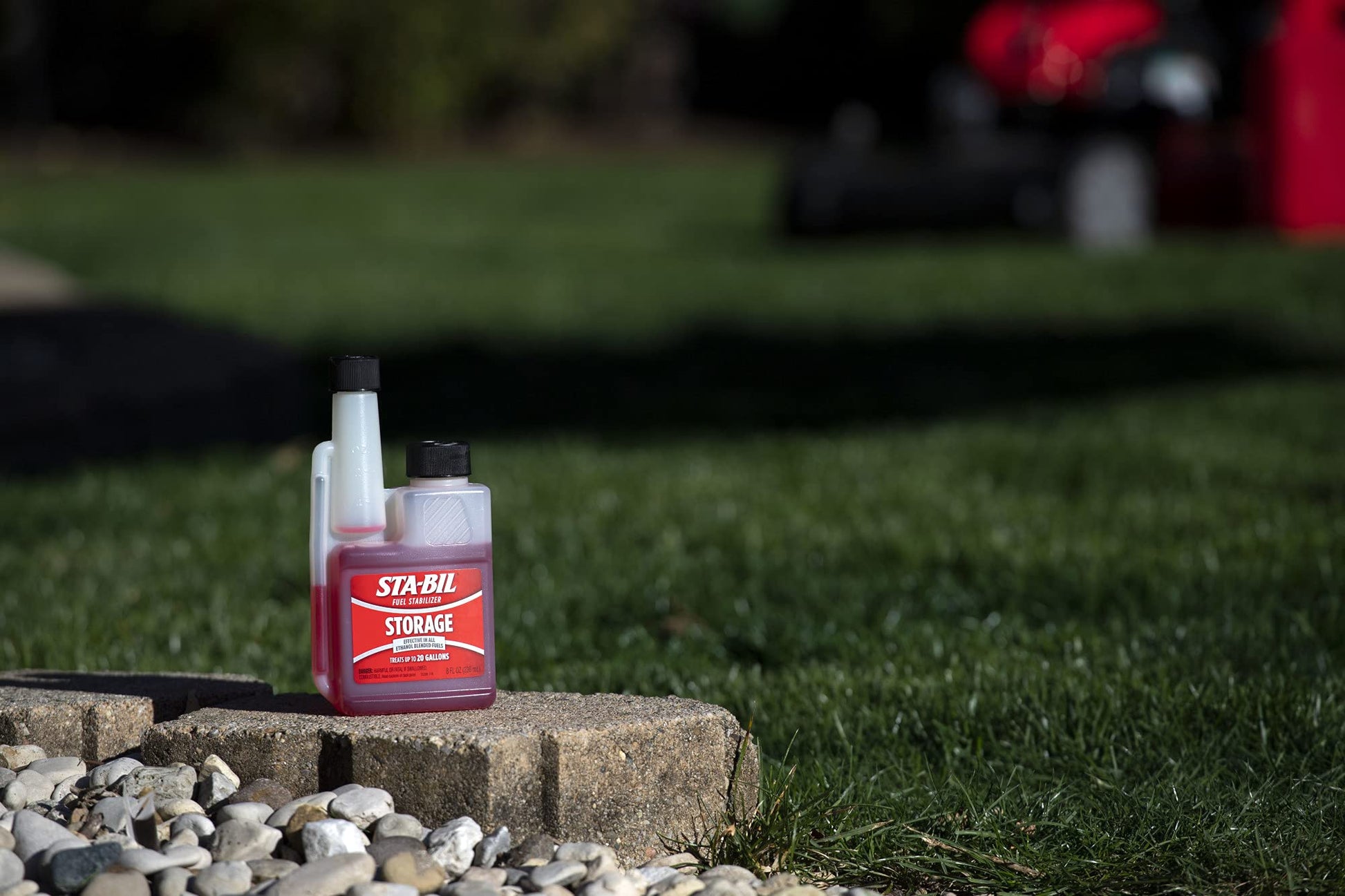 STA-BIL storage bottle on a stone ledge with grass 