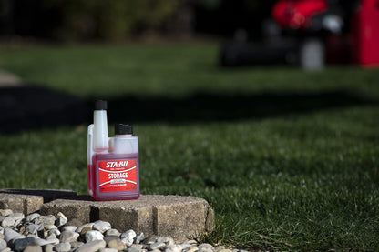 STA-BIL storage bottle on a stone ledge with grass 